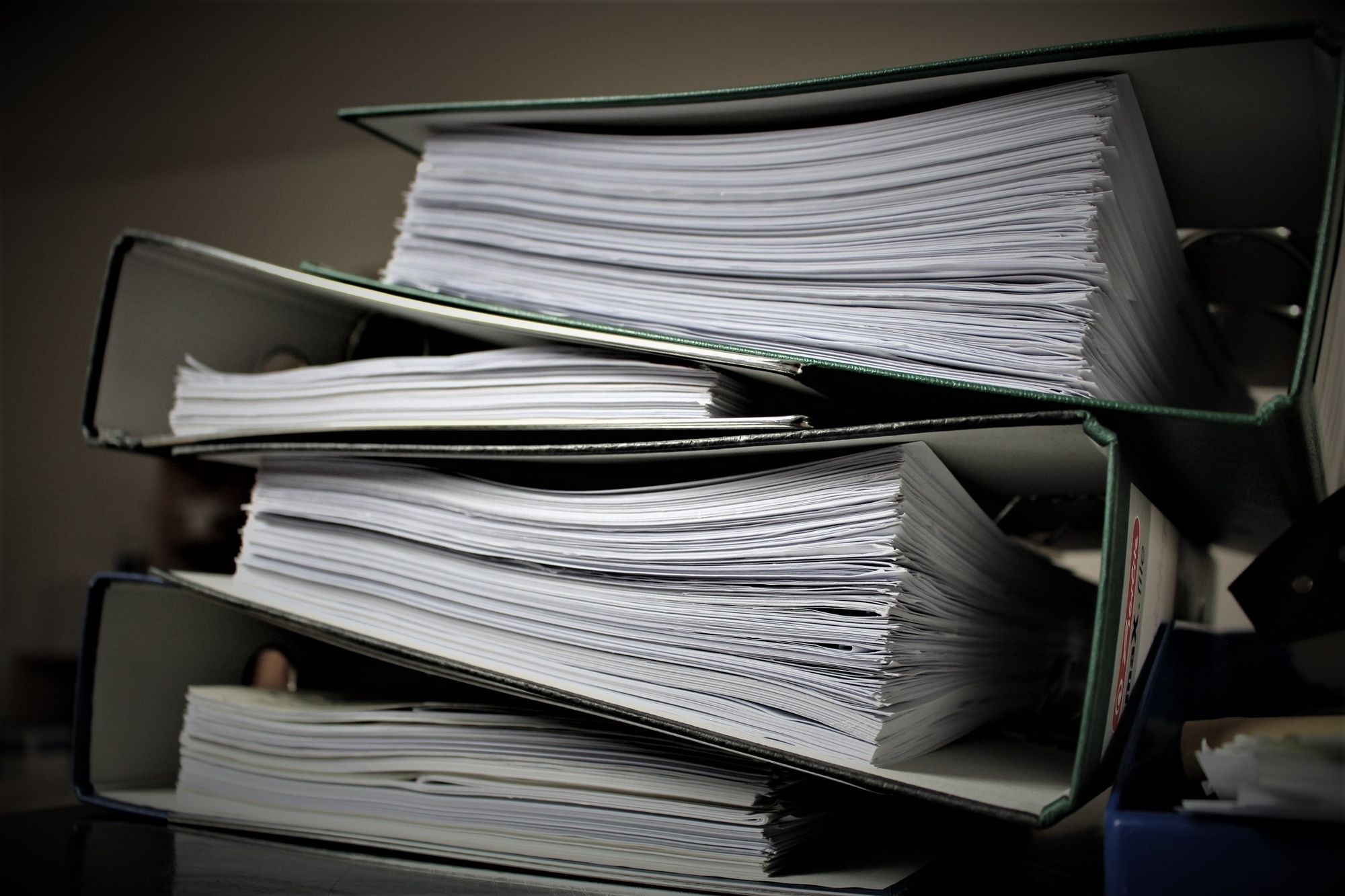 Aktenstapel und Ordner im Büro als Sinnbild für Bürokratieabbau im Unternehmen