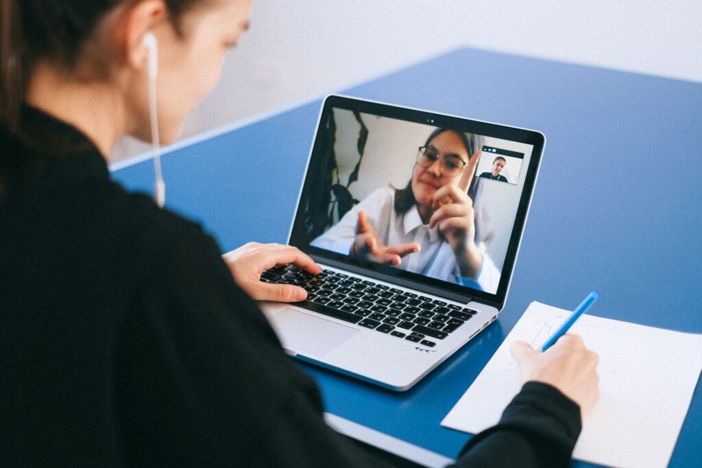 Hybrides Arbeiten: Team im Besprechungsraum im Videocall mit Kollegen am Laptop