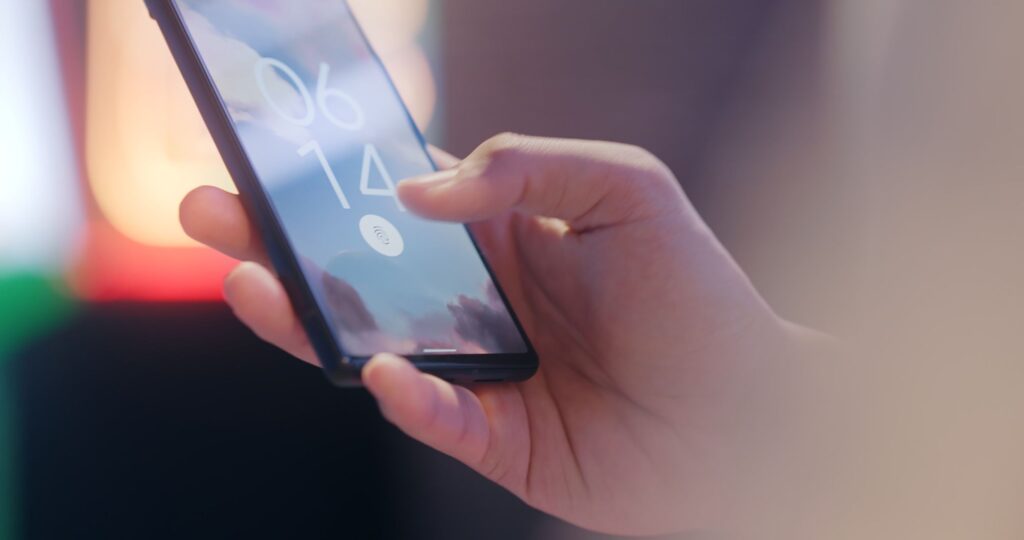 Hände halten ein Smartphone bei der Anmeldung: Passkeys ersetzen Passwörter im Unternehmen