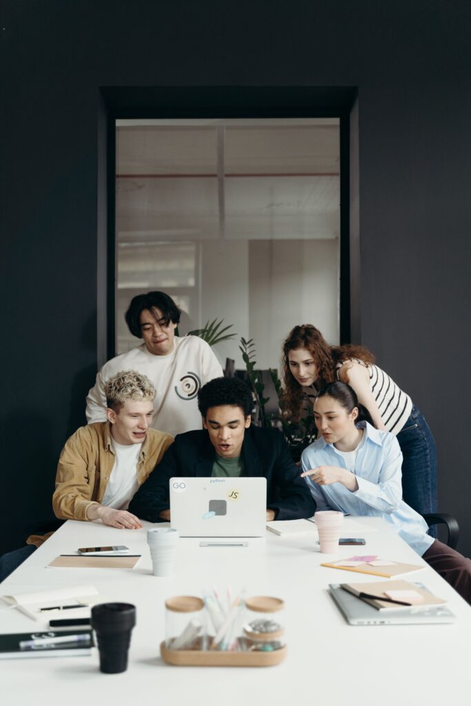 Junges Team arbeitet gemeinsam am Laptop und bespricht eine Startup-Kooperation mit dem Mittelstand