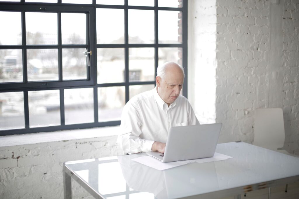 Aktivrente im Alltag: ernster älterer Mann arbeitet am Laptop im Büro