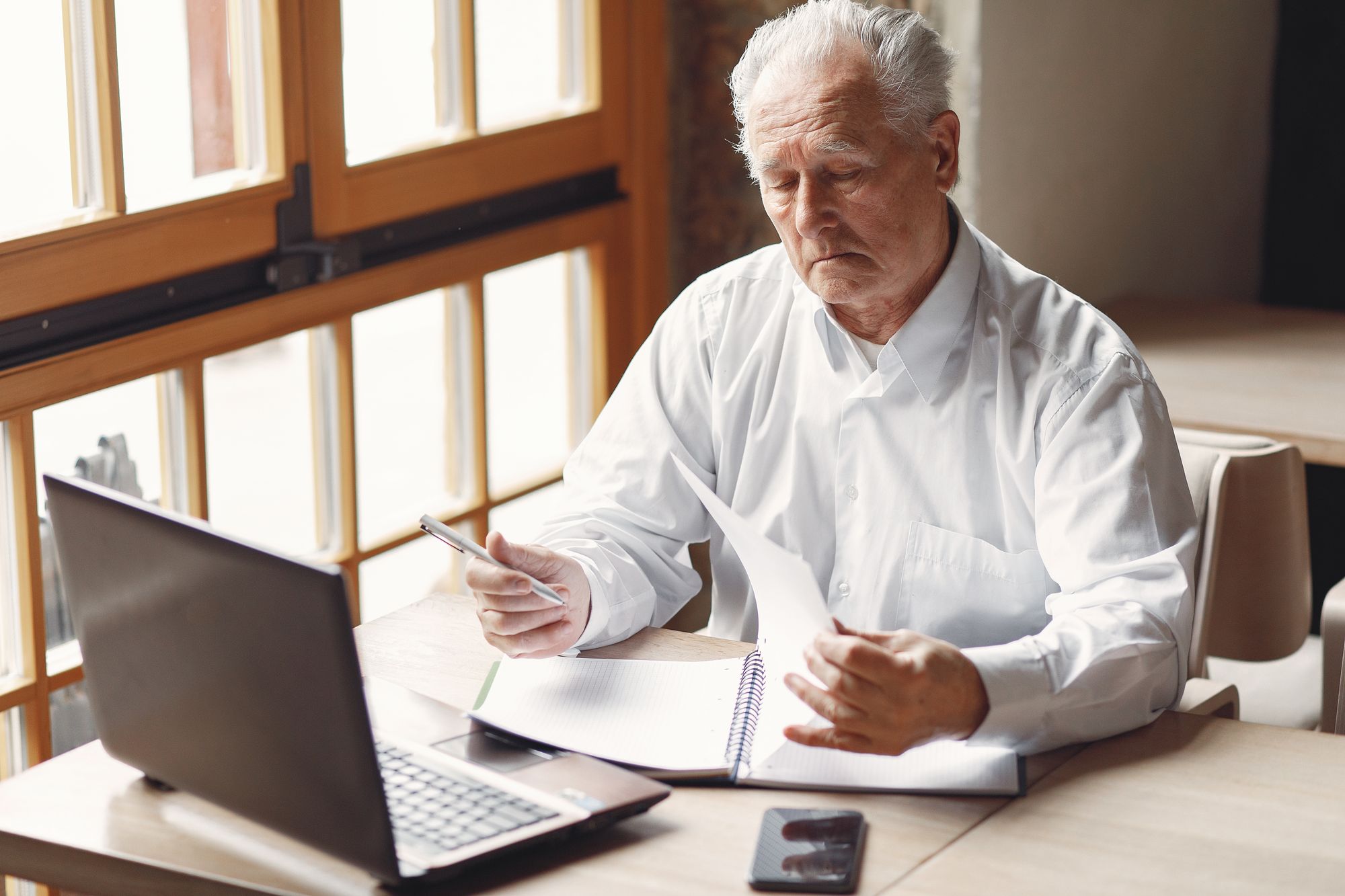 Aktivrente: Konzentrierter älterer Geschäftsmann arbeitet in einem modernen Büro