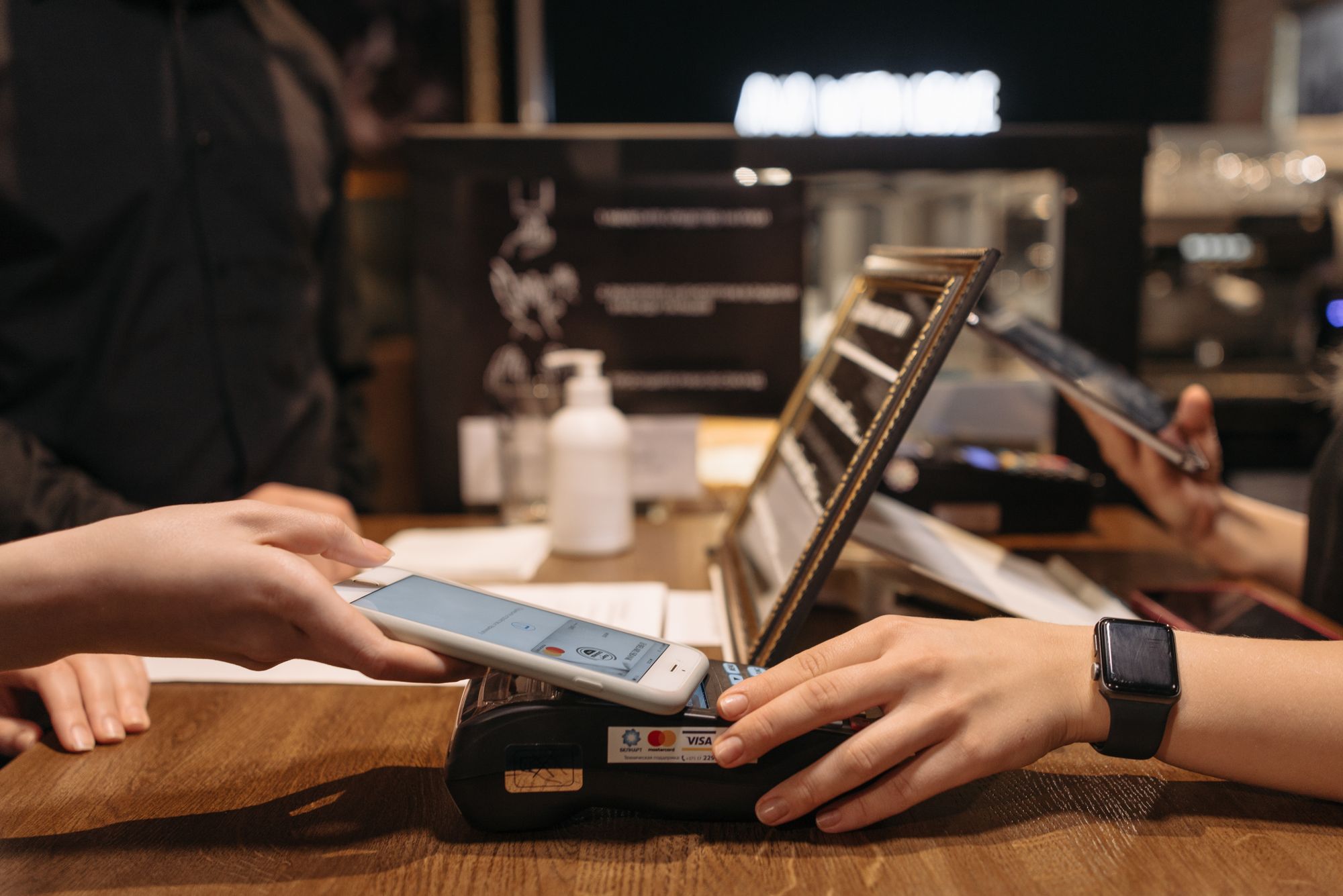 Embedded Finance im Alltag: Person hält Smartphone zum Bezahlen an ein Kartenterminal