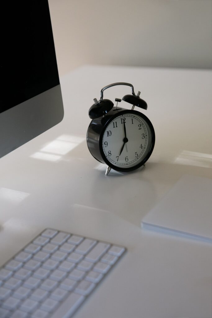 Schwarzer Wecker auf dem Schreibtisch als Symbol für die Höchstarbeitszeit im Büro
