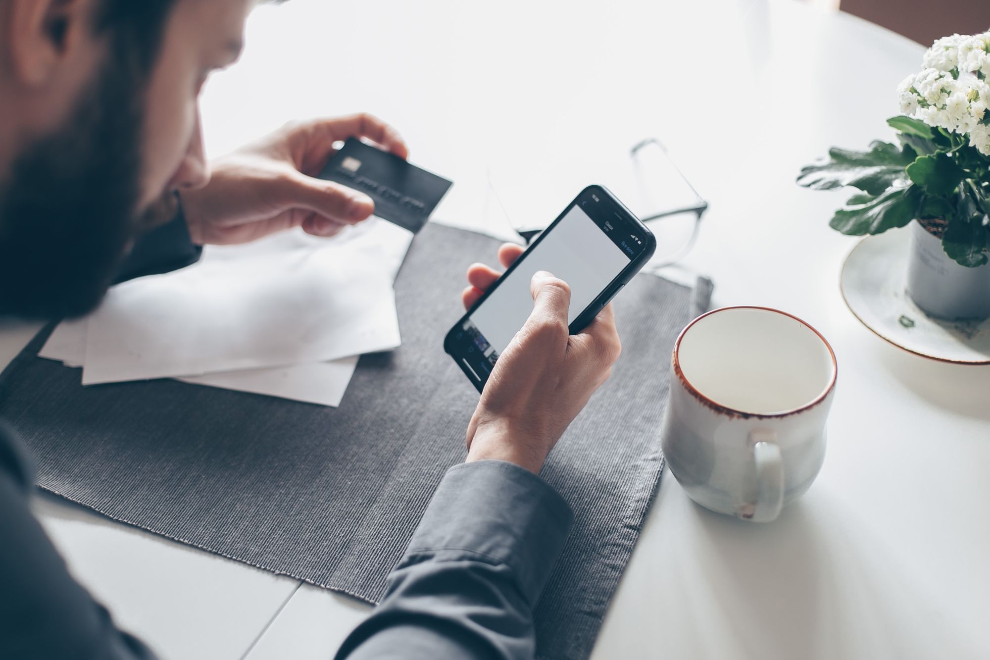 Instant Payment per Smartphone: Mann hält Smartphone und Kreditkarte in den Händen