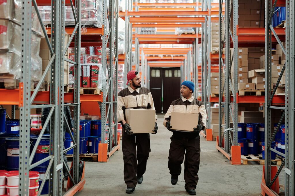 Lagerarbeiter tragen Kartons, die Lohnnebenkosten ihrer Stellen trägt der Arbeitgeber