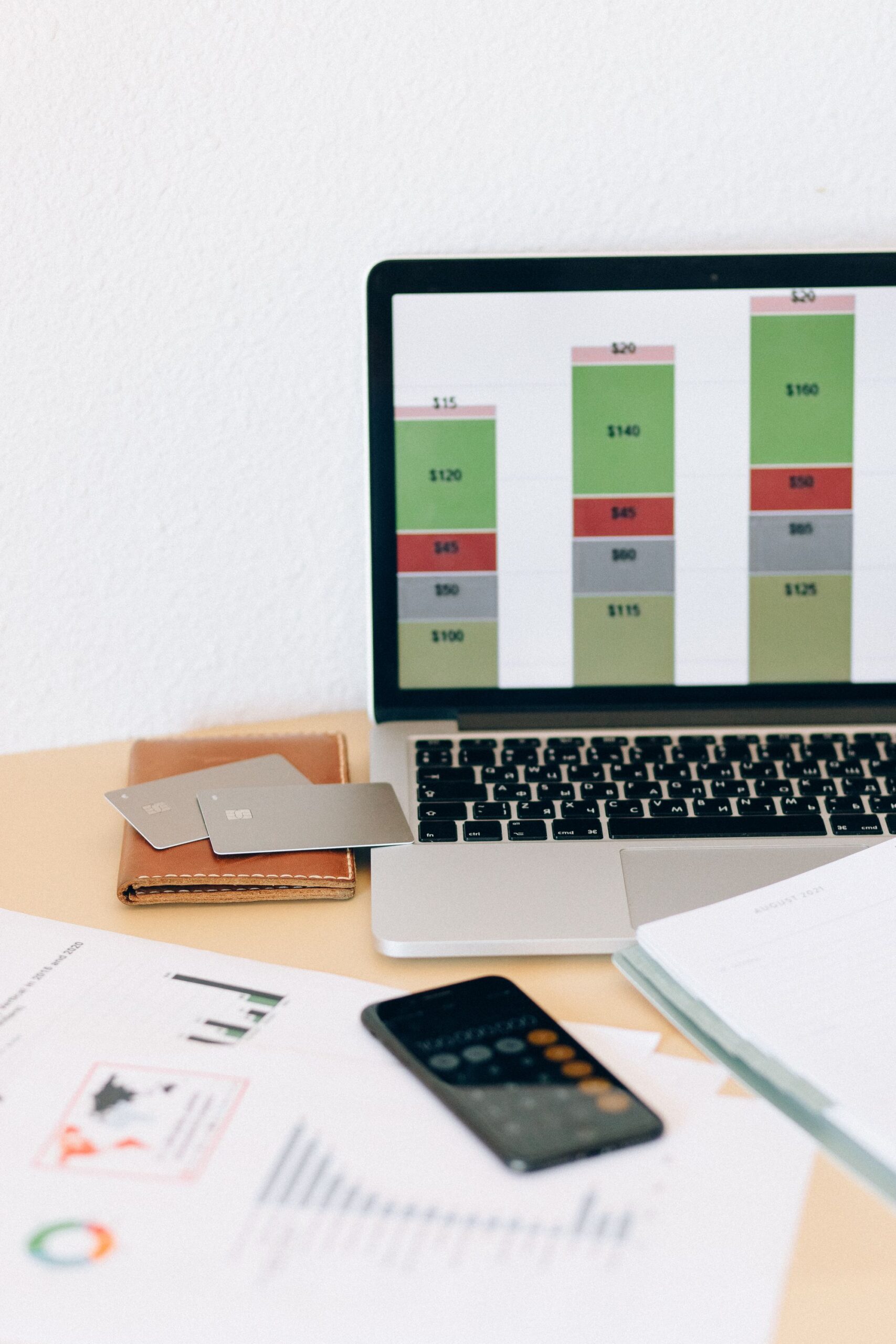 Open Banking: Laptop mit Finanzdiagramm neben Dokumenten und Kreditkarten