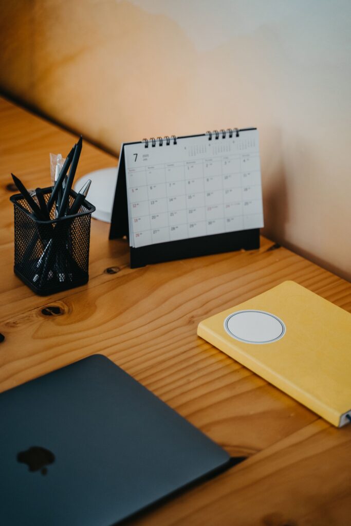 Laptop und Kalender auf Holztisch beim Berechnen von Urlaubsanspruch im Team