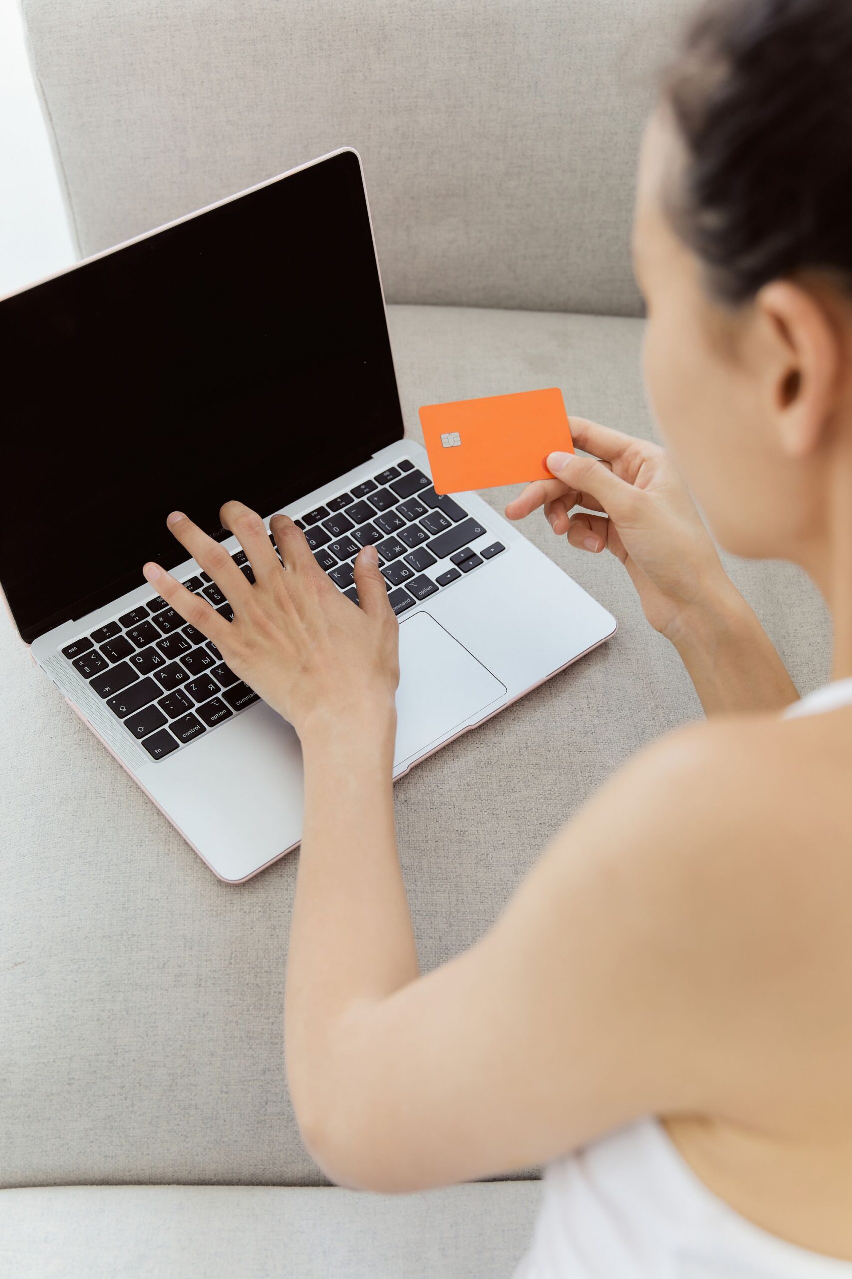 Verification of Payee: Frau hält Bankkarte und nutzt Onlinebanking am Laptop
