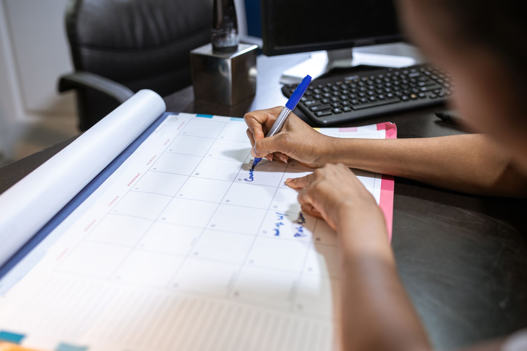 Vier-Tage-Woche planen: Person schreibt Termine in einen Tischkalender